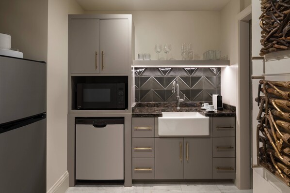 A compact kitchen with a microwave, dishwasher, and a sink with a towel.