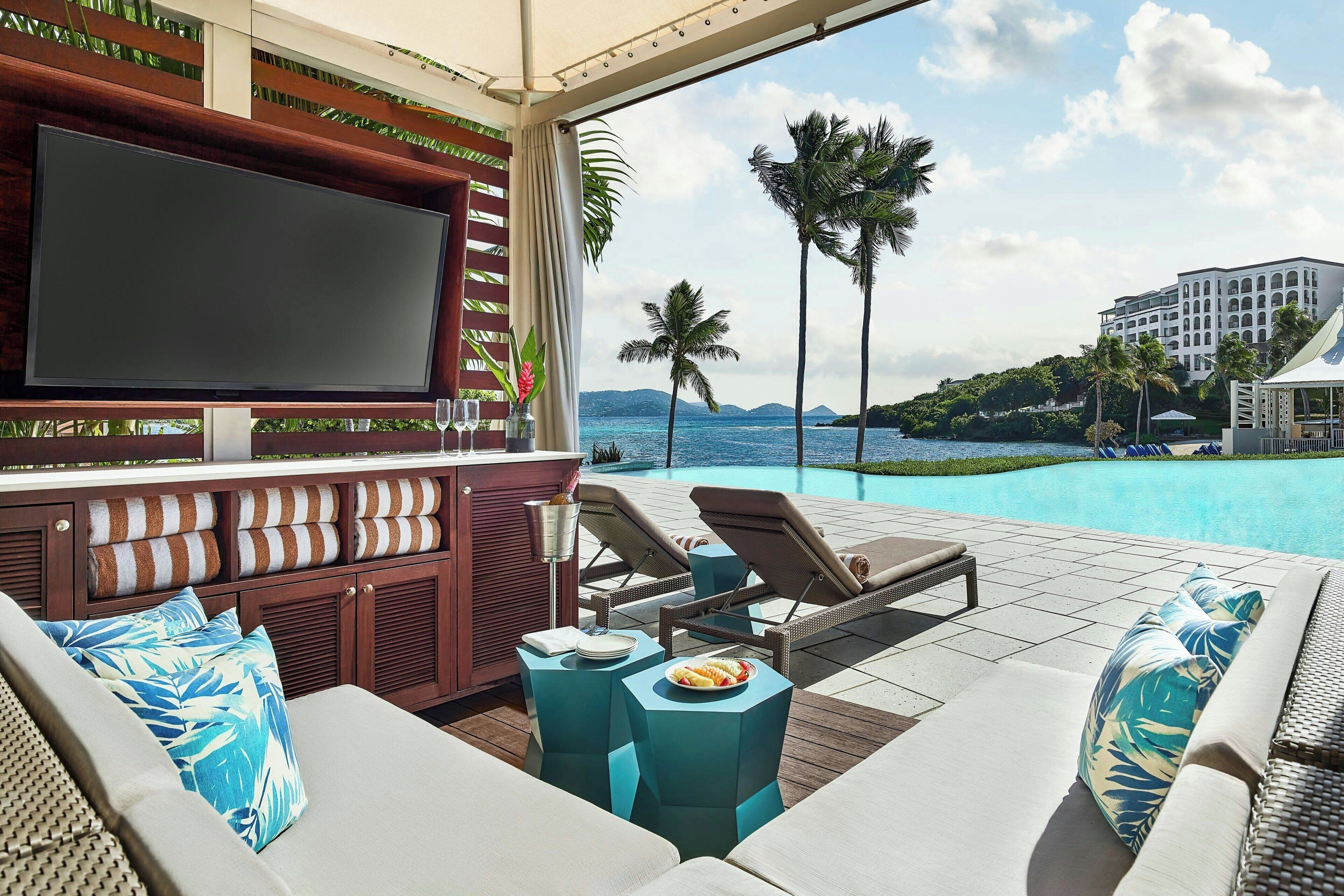 A poolside area with a TV, lounge chairs, and a buffet table.
