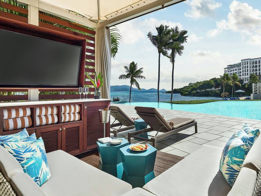 A poolside area with a TV, lounge chairs, and a buffet table.