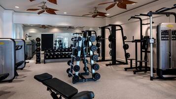 A gym with ceiling fans, weightlifting equipment, and a mirror.