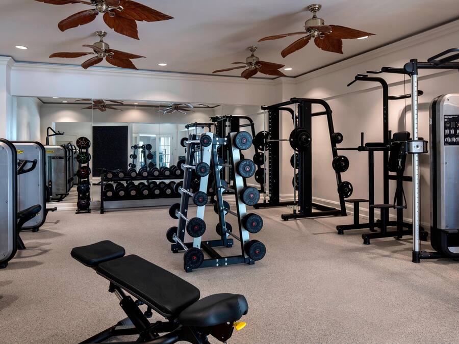 A gym with ceiling fans, weightlifting equipment, and a mirror.