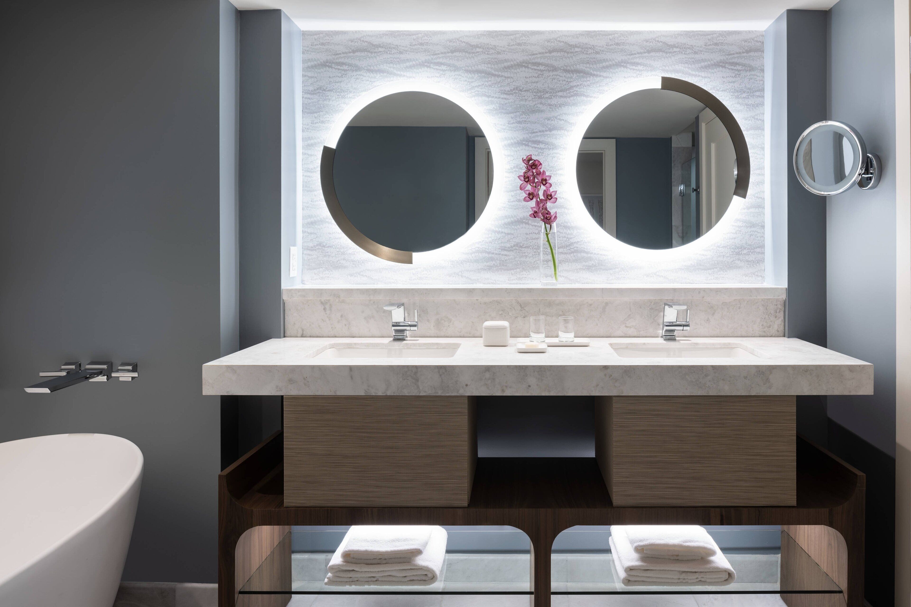 Une salle de bain moderne dotée d’un grand miroir, de deux vasques et d’une douche à l’italienne.