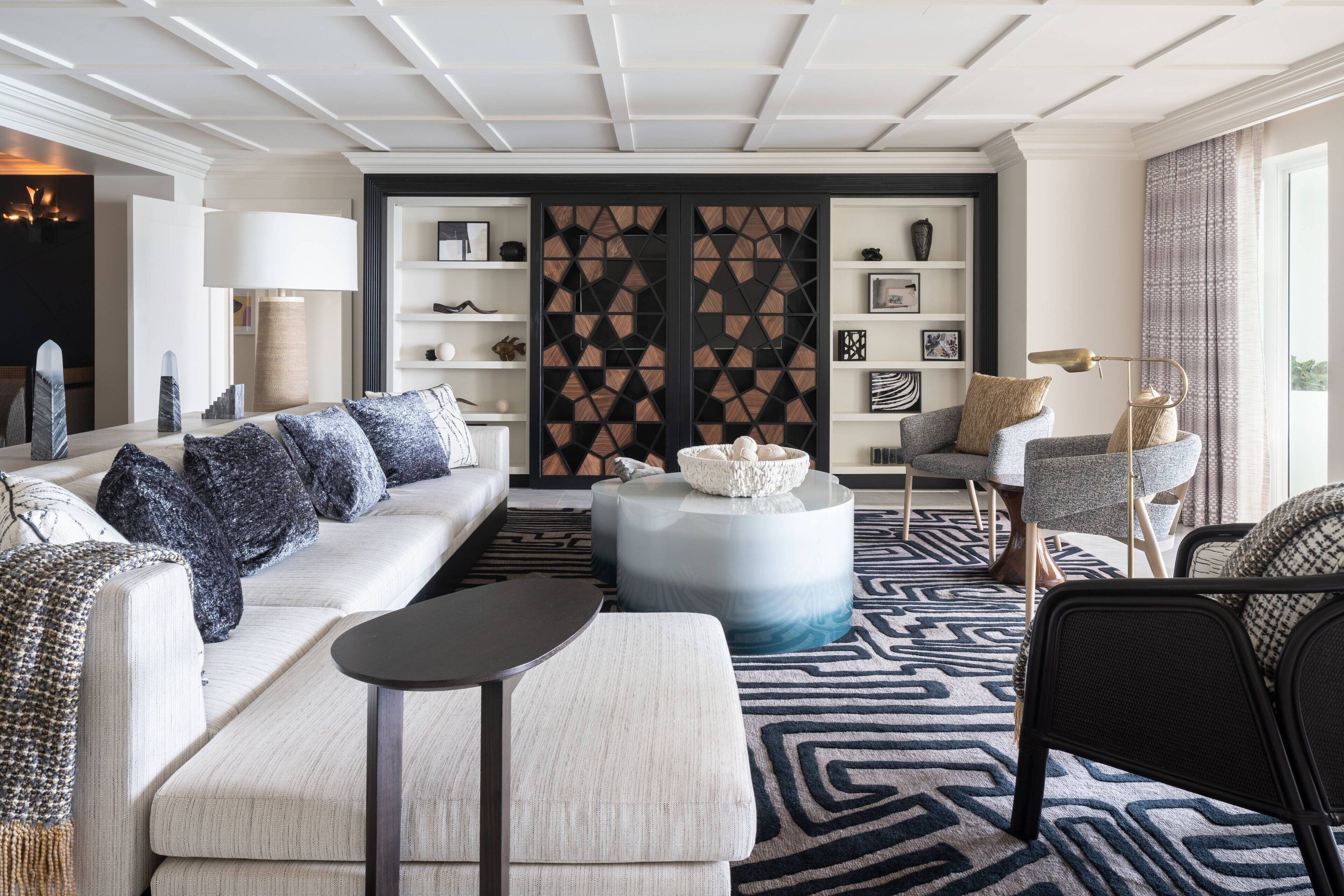 Ein modernes Wohnzimmer mit einem weißen Sofa, einem runden Couchtisch und einem gemusterten Teppich.