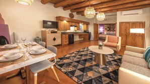 Una cocina moderna con armarios de madera, un comedor con mesa redonda y una sala de estar con sofá y alfombra estampada.