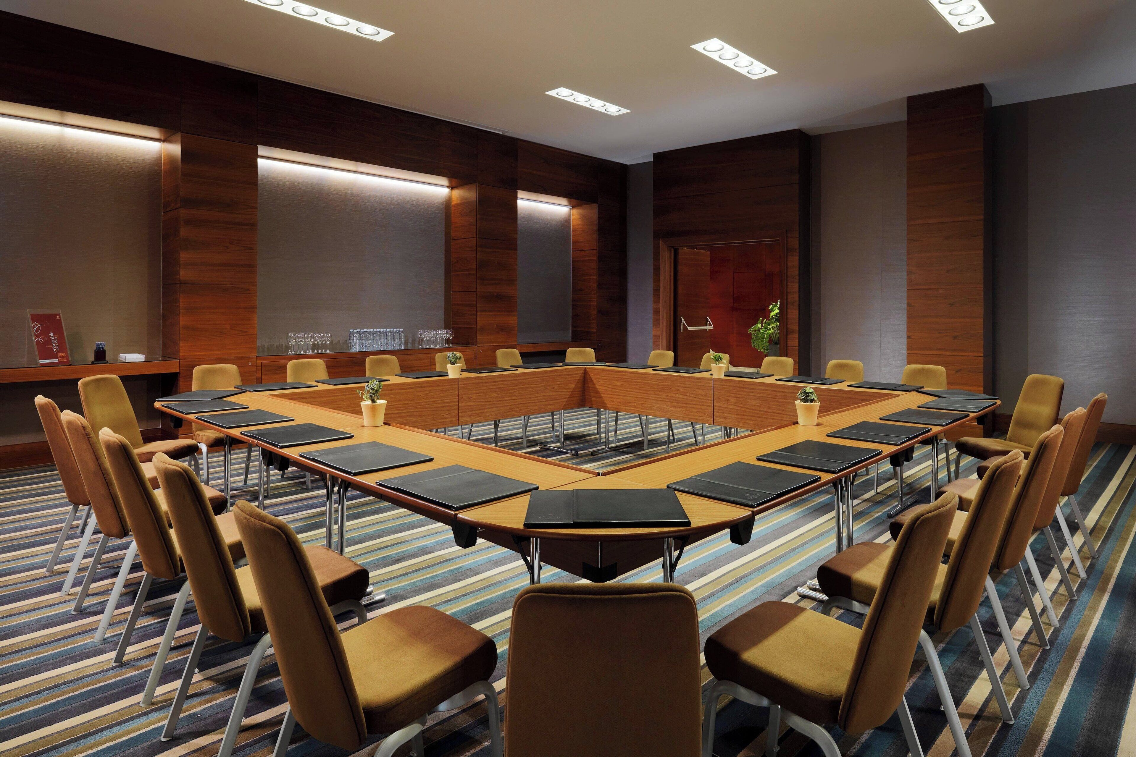 Una sala de conferències amb una taula ovalada gran, diverses cadires i un paviment amb moqueta.