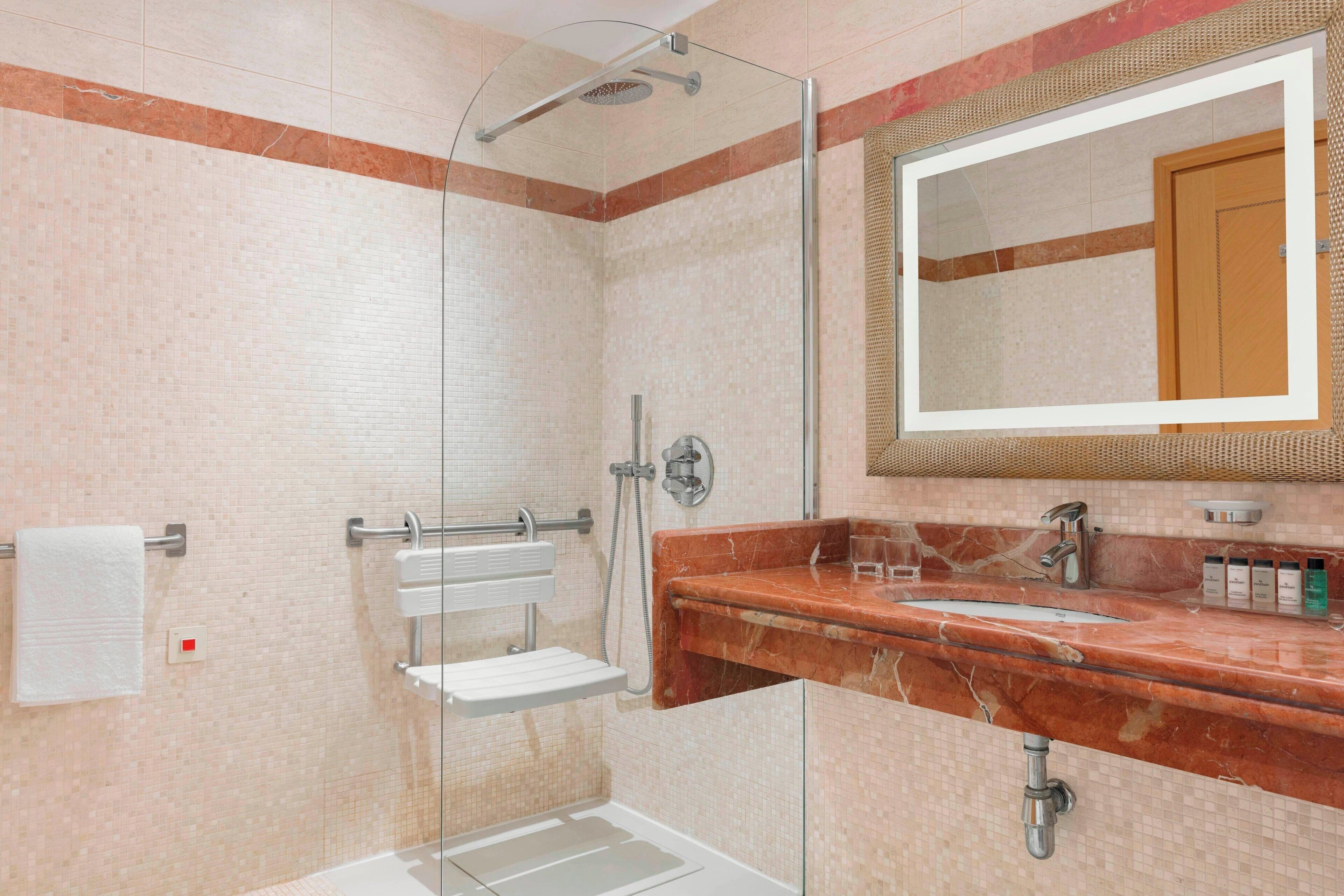 A bathroom with a glass-enclosed shower, a marble sink, and a large mirror.