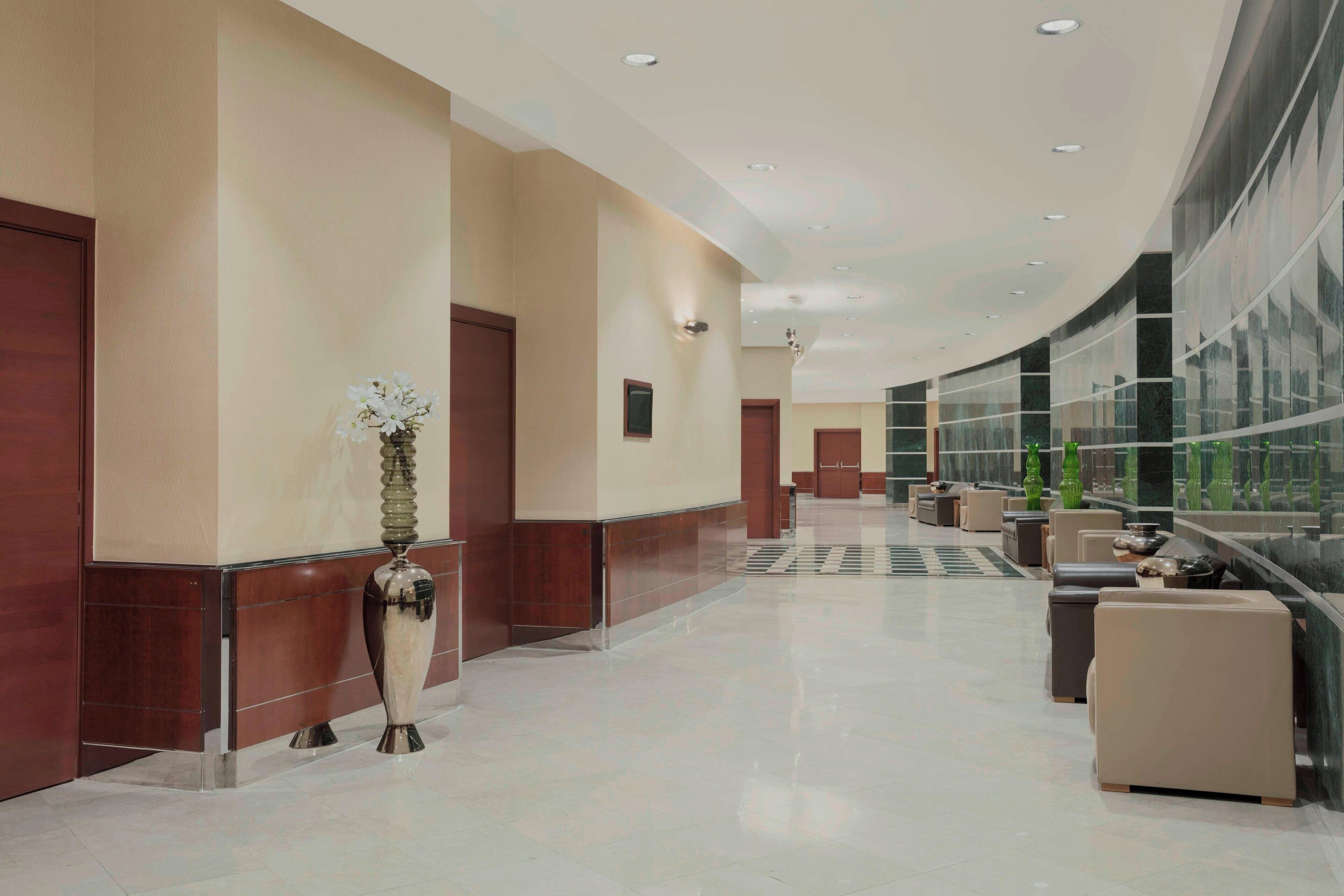 A modern hotel lobby with a curved ceiling, a reception desk, and seating areas.