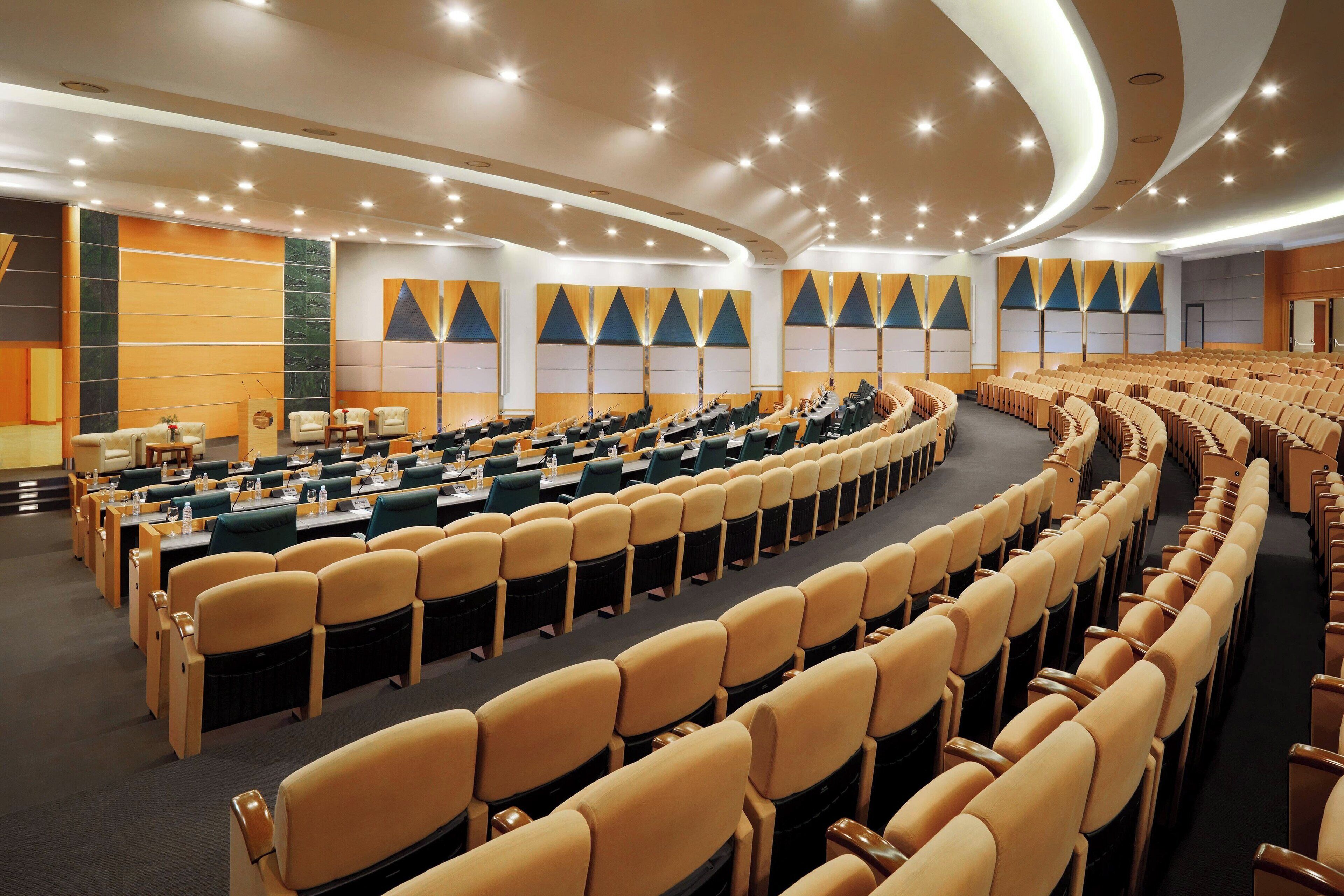 A conference room with rows of chairs, tables, and a stage.