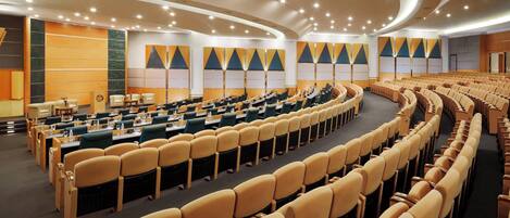 A conference room with rows of chairs, tables, and a stage.