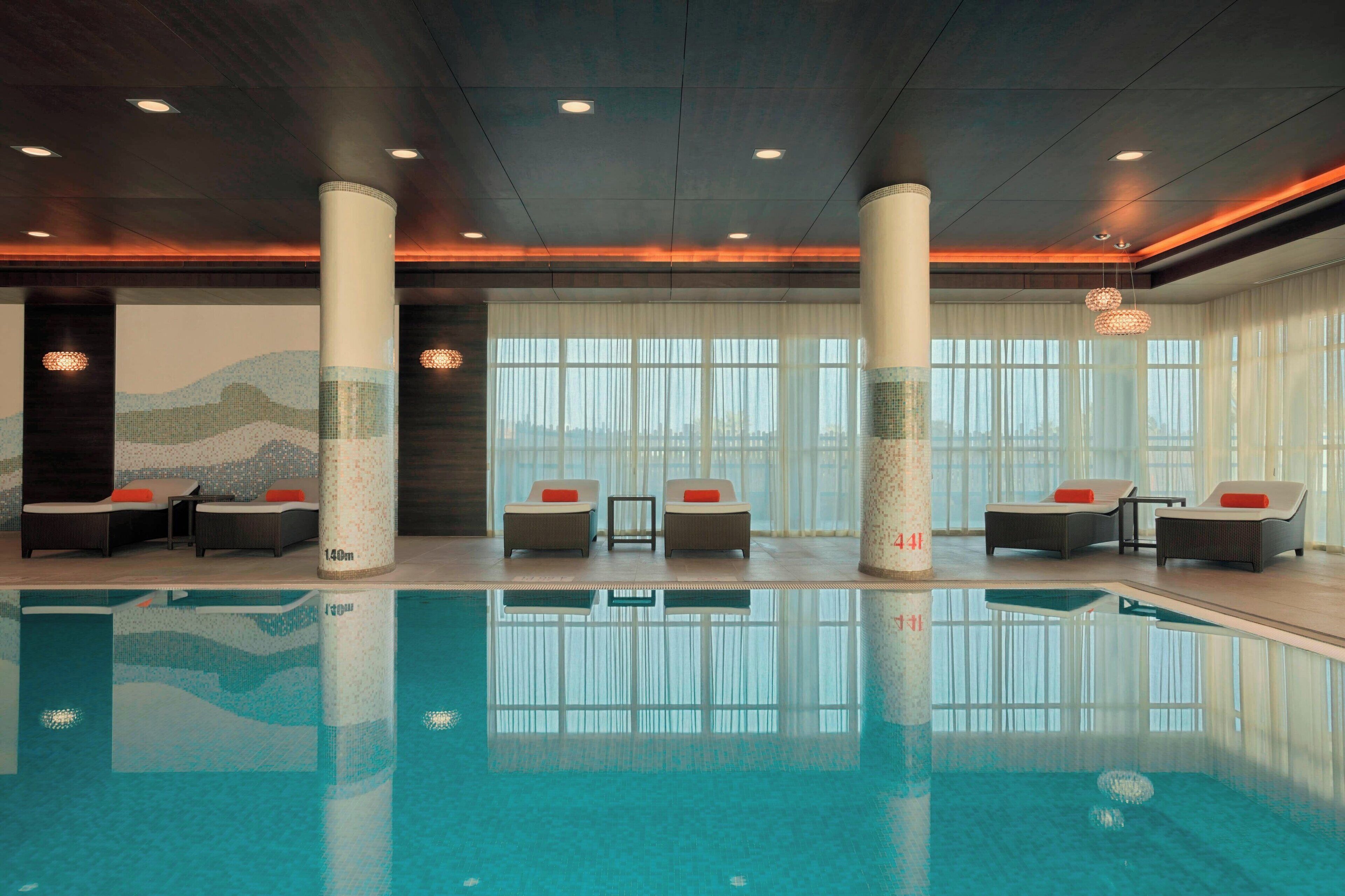 Una piscina interior con sillones de descanso y vistas de la ciudad.