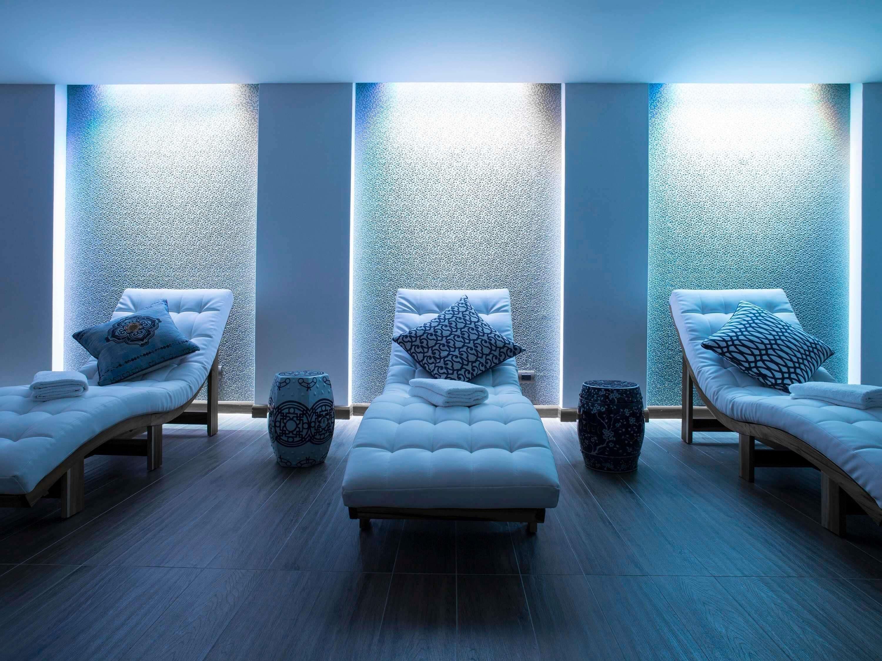 Ein Spa-Raum mit drei Liegestühlen, jeweils mit einem gemusterten Kissen und einer kleinen Dekorationsvase.