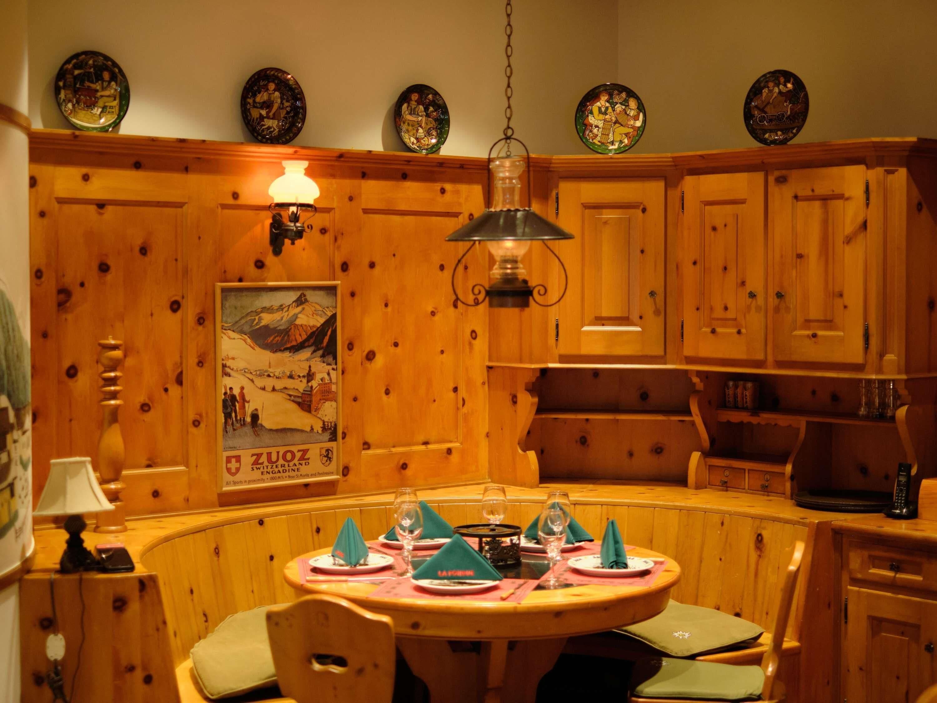 A wooden dining area with a round table set for four, wooden cabinets, and a wall-mounted light fixture.