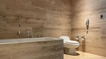 Uma casa de banho moderna com uma banheira grande, uma sanita e um chuveiro.