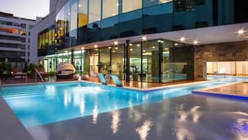 Una piscina cubierta, una piscina al aire libre, tumbonas