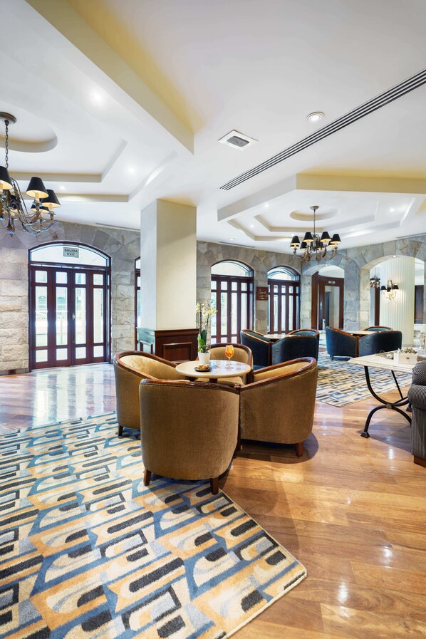 A spacious lobby with a patterned carpet, multiple seating areas, and a stone wall. - Swissôtel Lima (Lima)