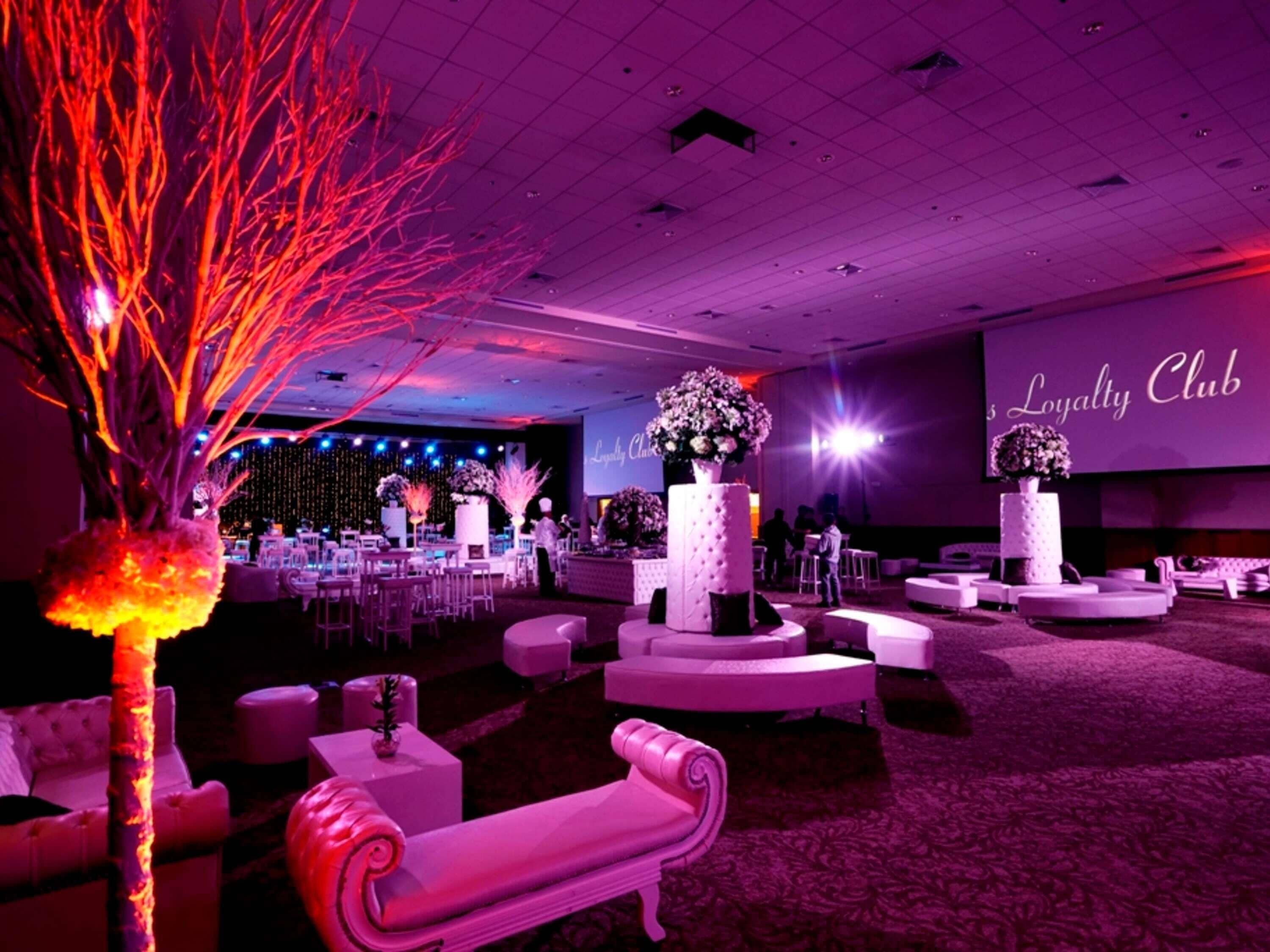 Una amplia sala de eventos con asientos escalonados, un escenario y una gran pantalla mostrando 'Loyalty Club'.