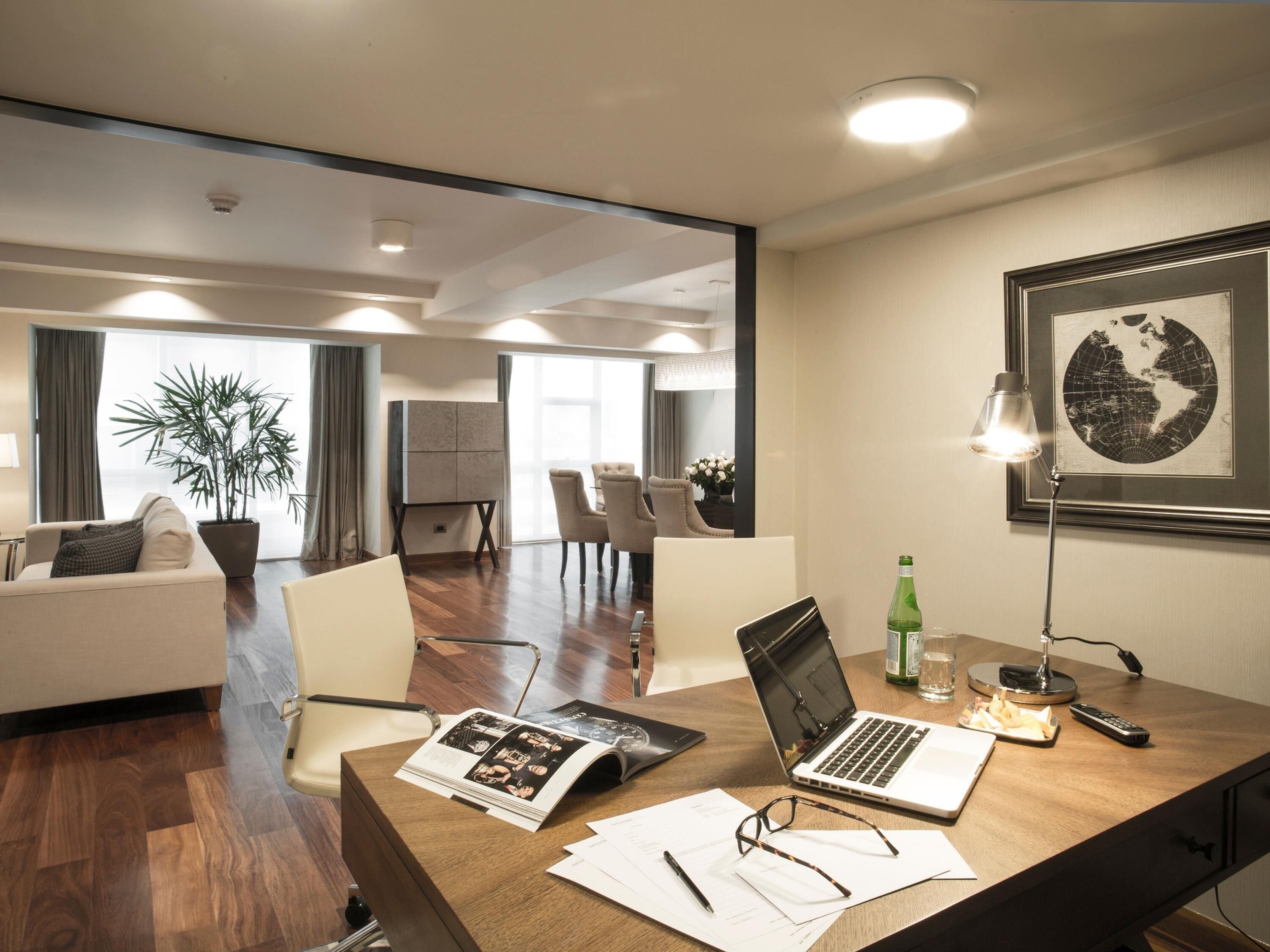 Um espaço de escritório moderno com escrivaninha de madeira, laptops e um mapa emoldurado na parede.