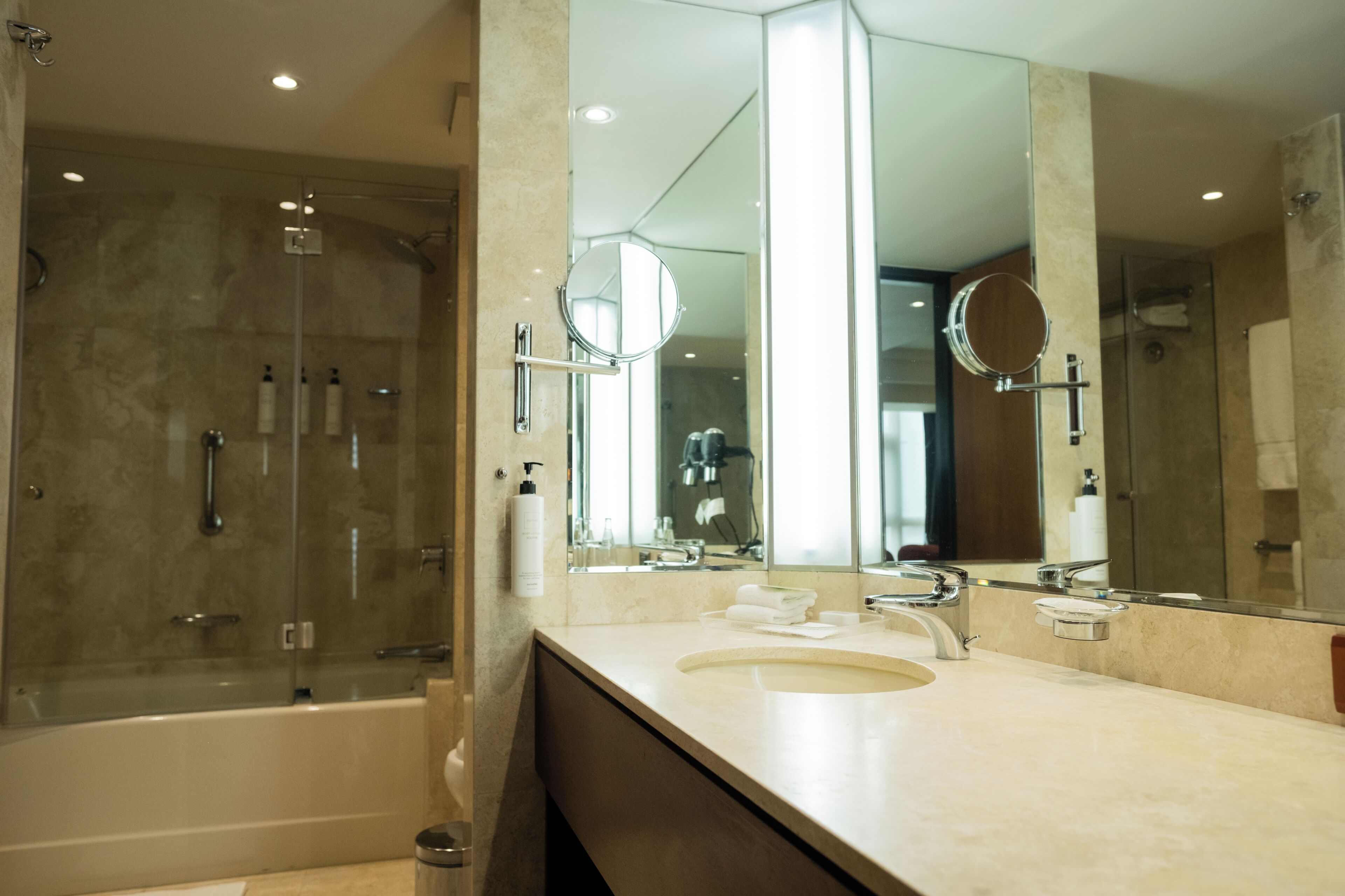 Une salle de bain moderne avec une baignoire, un grand miroir et un lavabo.