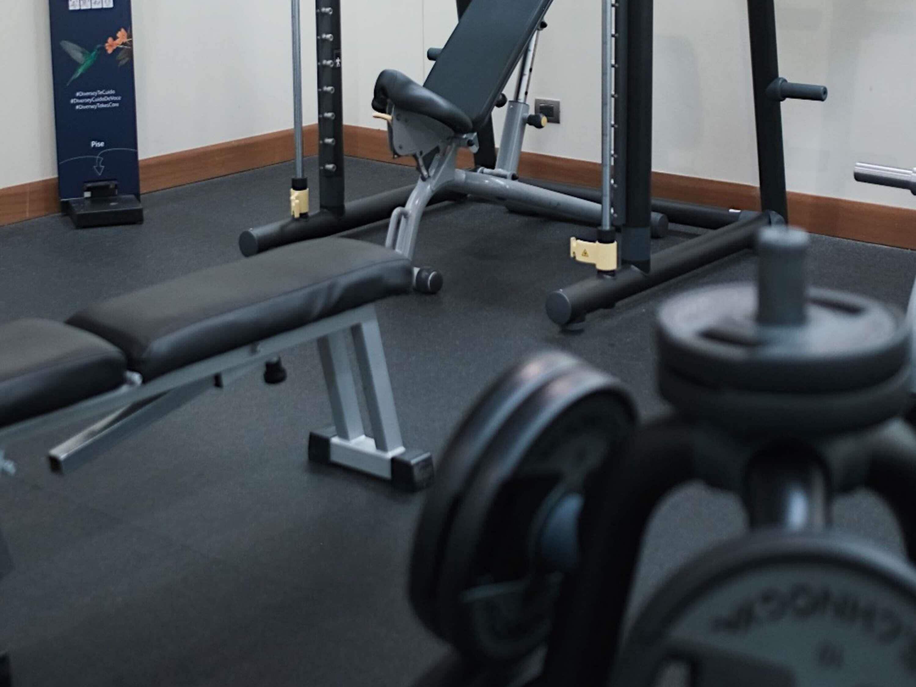 A gym with a bench, weight rack, and a poster on the wall.