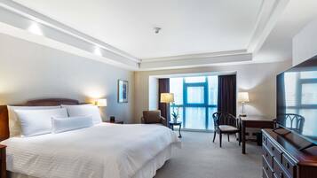 Une chambre d’hôtel équipée d’un lit, d’un bureau, d’une chaise, d’une commode et d’une grande fenêtre.