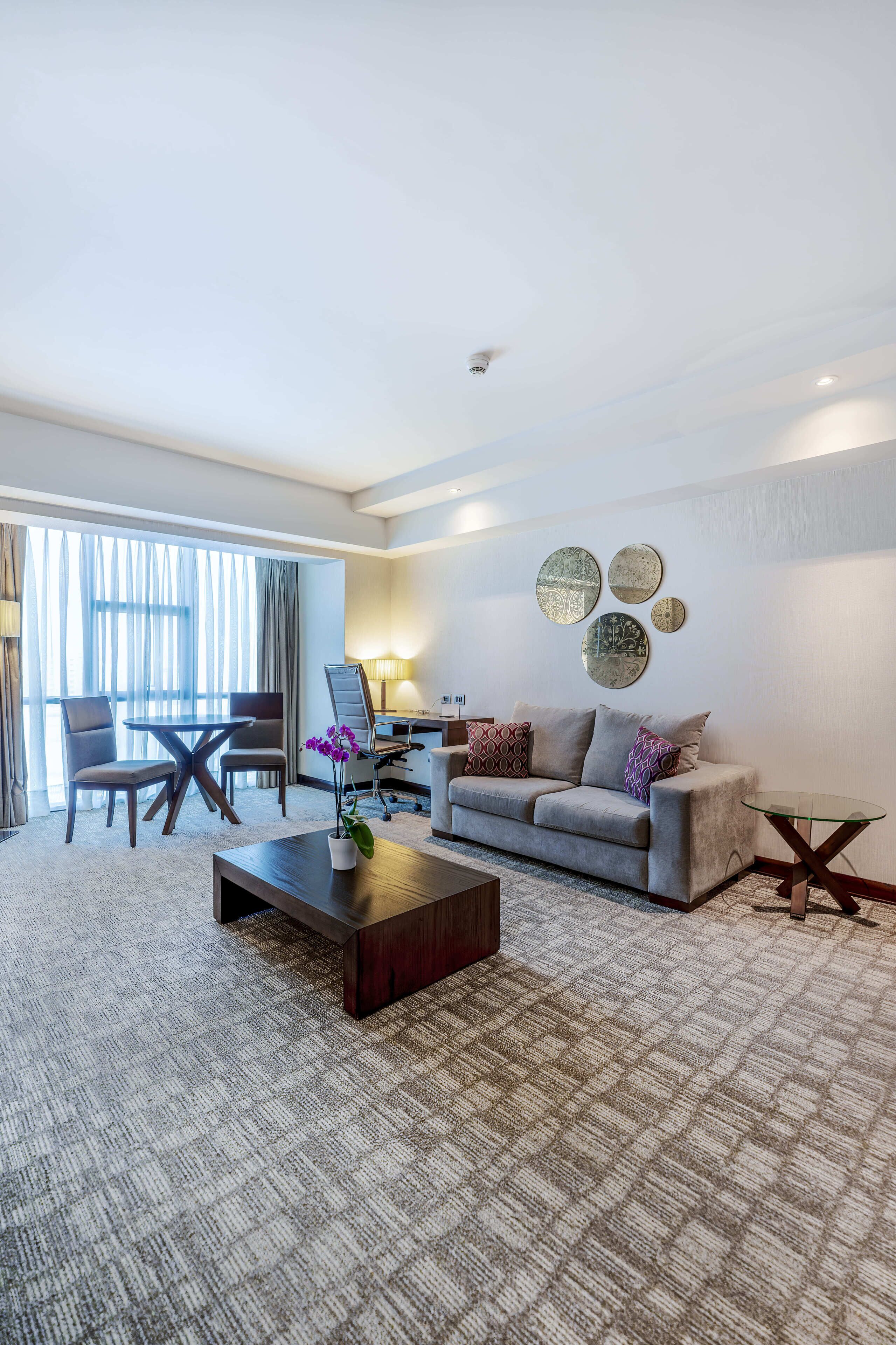 A hotel room with a sofa, a coffee table, a desk, and a chair.