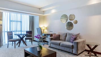 A hotel room with a sofa, a coffee table, a desk, and a chair.