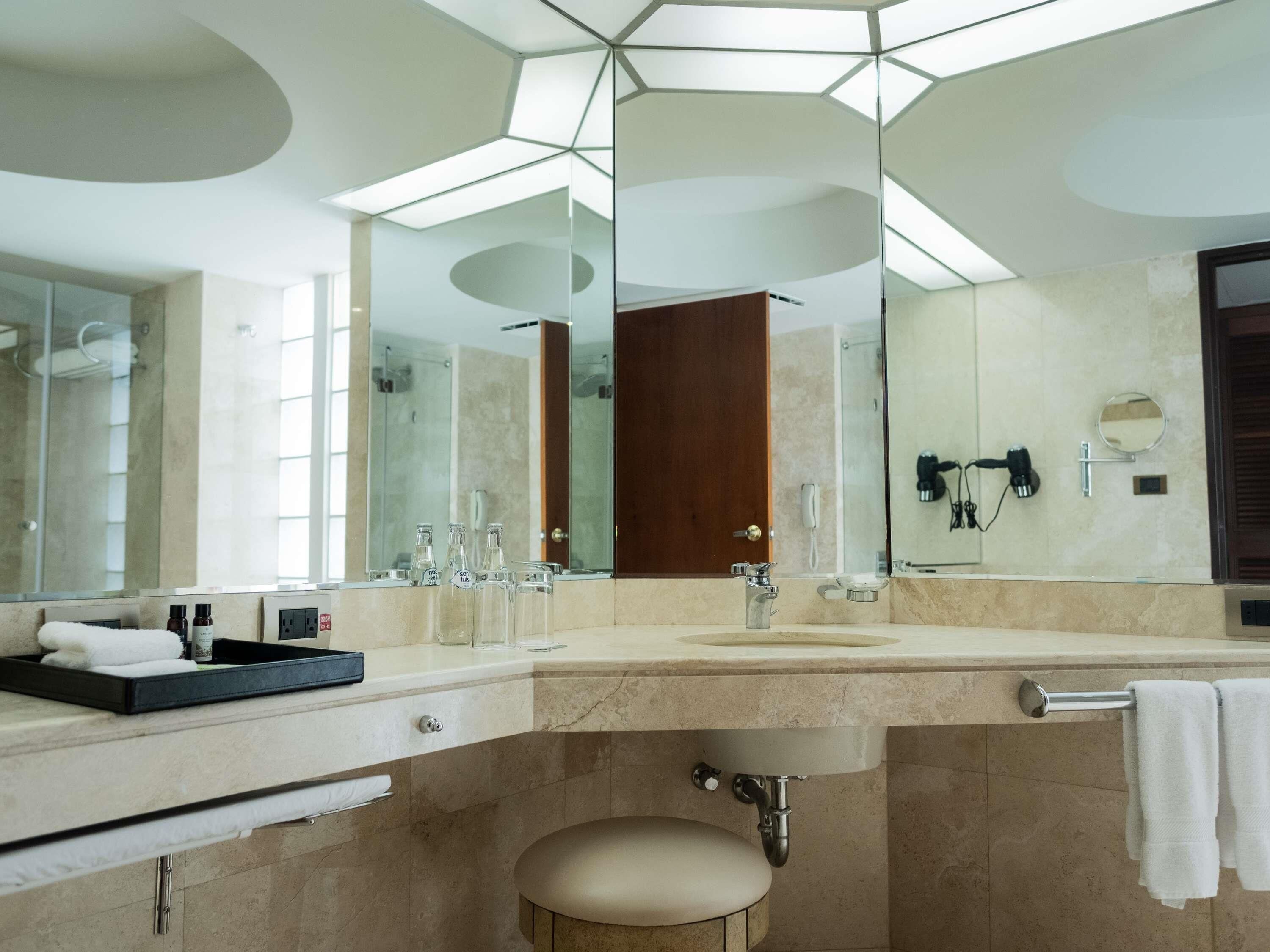 Un baño moderno con un espejo grande, un lavamanos, un inodoro y una zona de ducha.