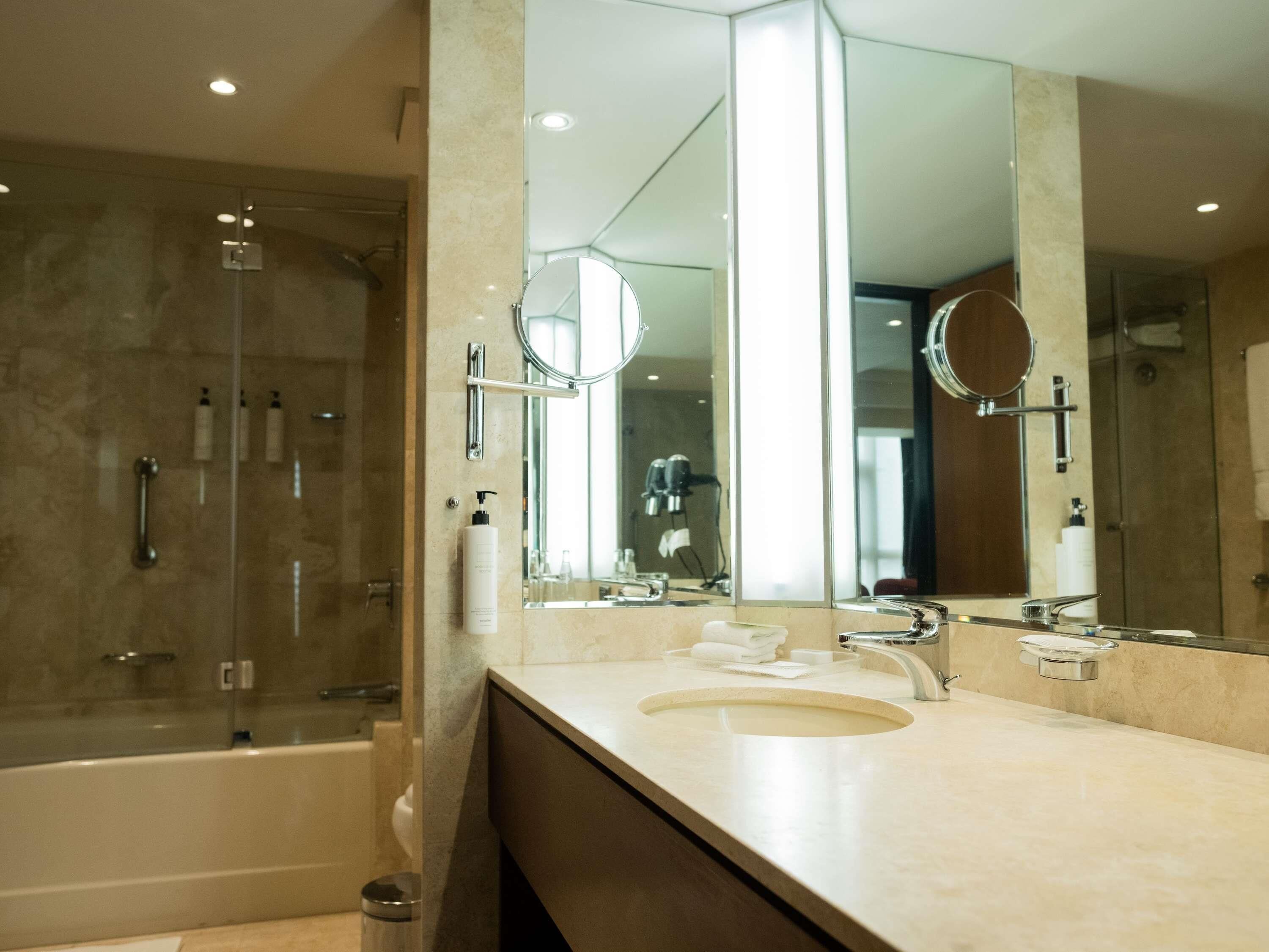 A modern bathroom with a bathtub, a large mirror, and a shower area.