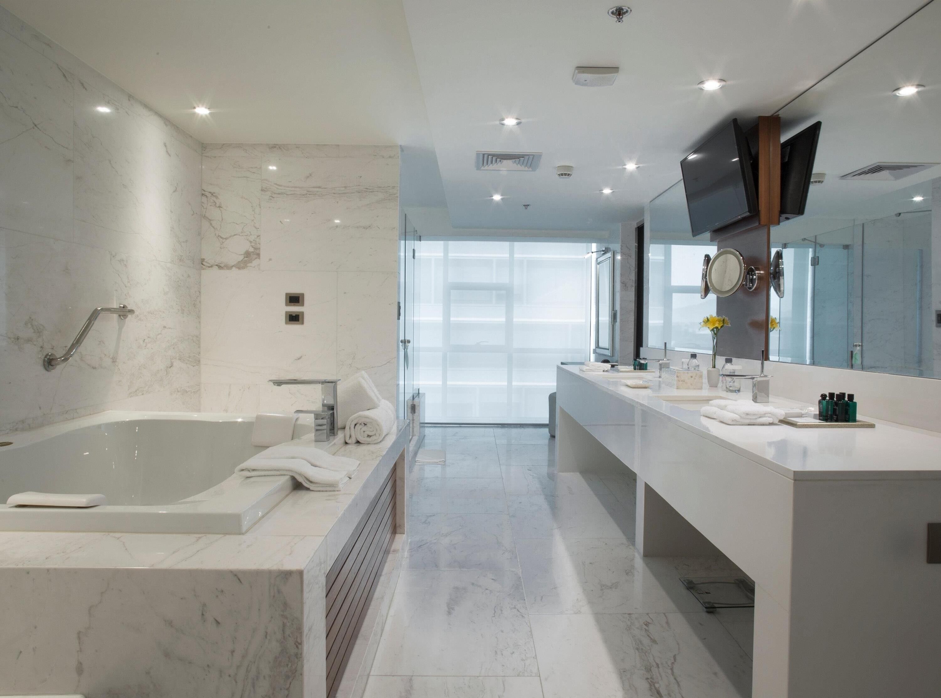 A modern bathroom with a large bathtub, a vanity with a mirror, and a shower area.
