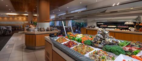 A buffet area with various food options, including salads, fruits, and seafood.