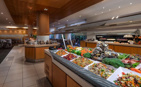 A buffet area with various food options, including salads, fruits, and seafood.