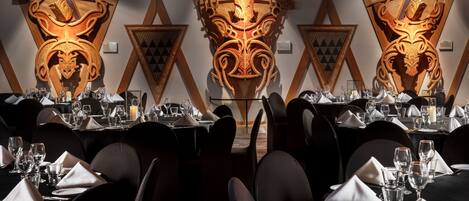 A dining area with tables set for a meal, featuring ornate wall decorations and a modern design.