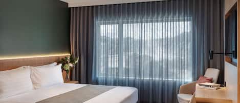 A modern hotel room with a large bed, a desk, and a chair.