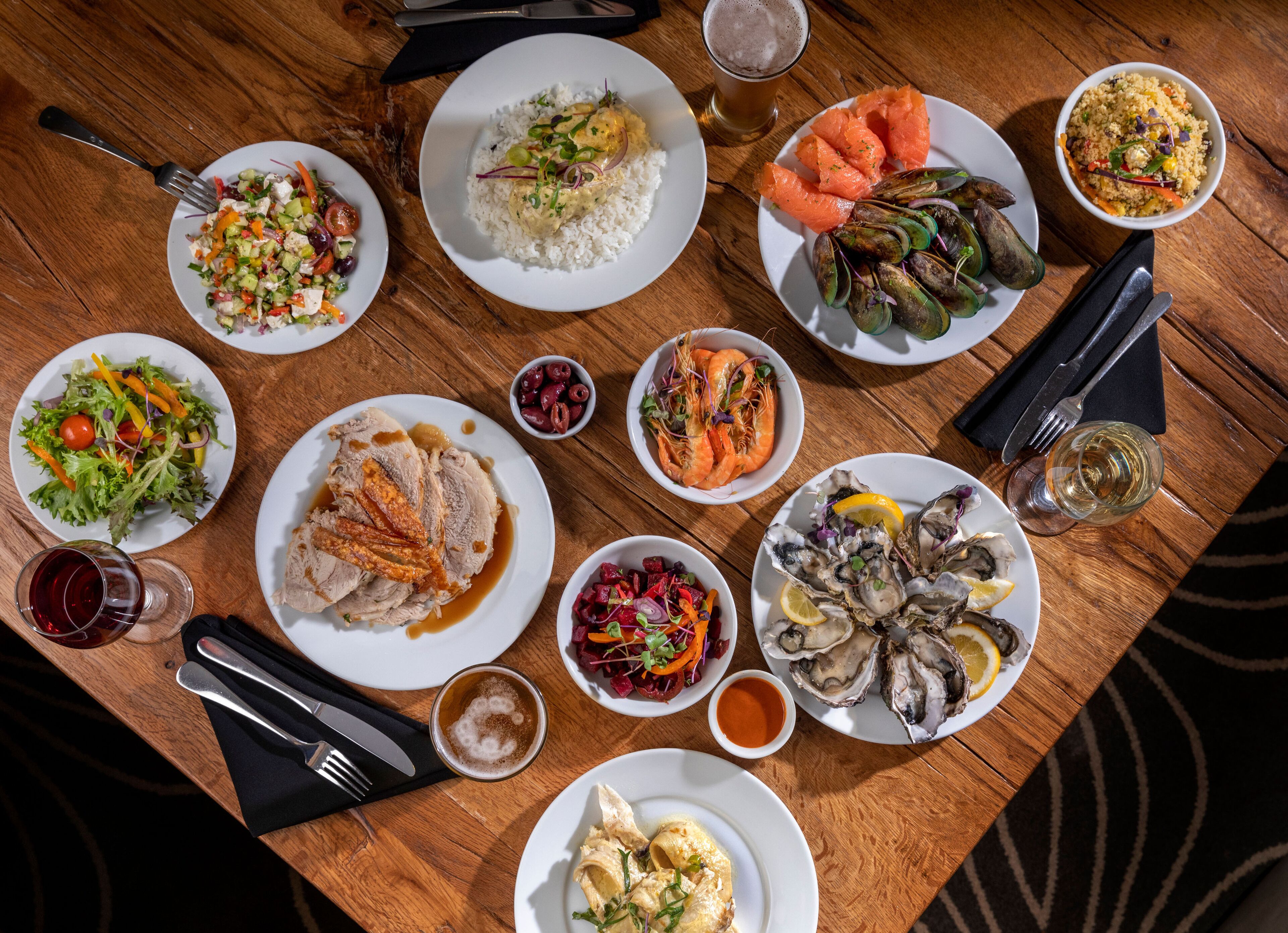 A variety of dishes on a wooden table, including seafood, rice, and salads.