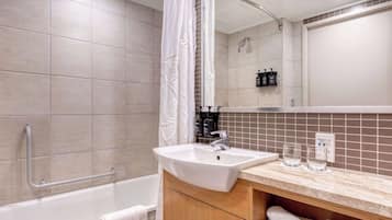 A modern bathroom with a bathtub, a sink, and a vanity with towels.