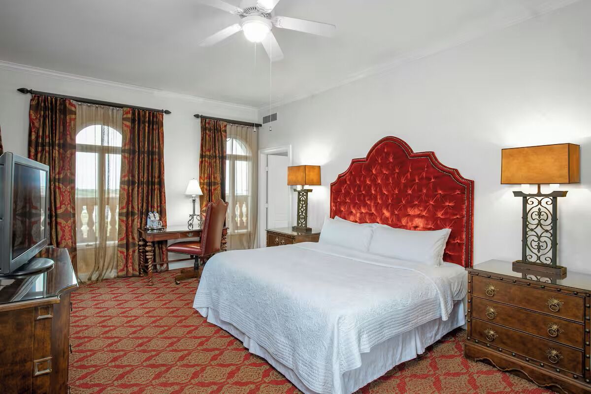 Une chambre d’hôtel avec un grand lit, une télévision, un bureau et deux lampes.