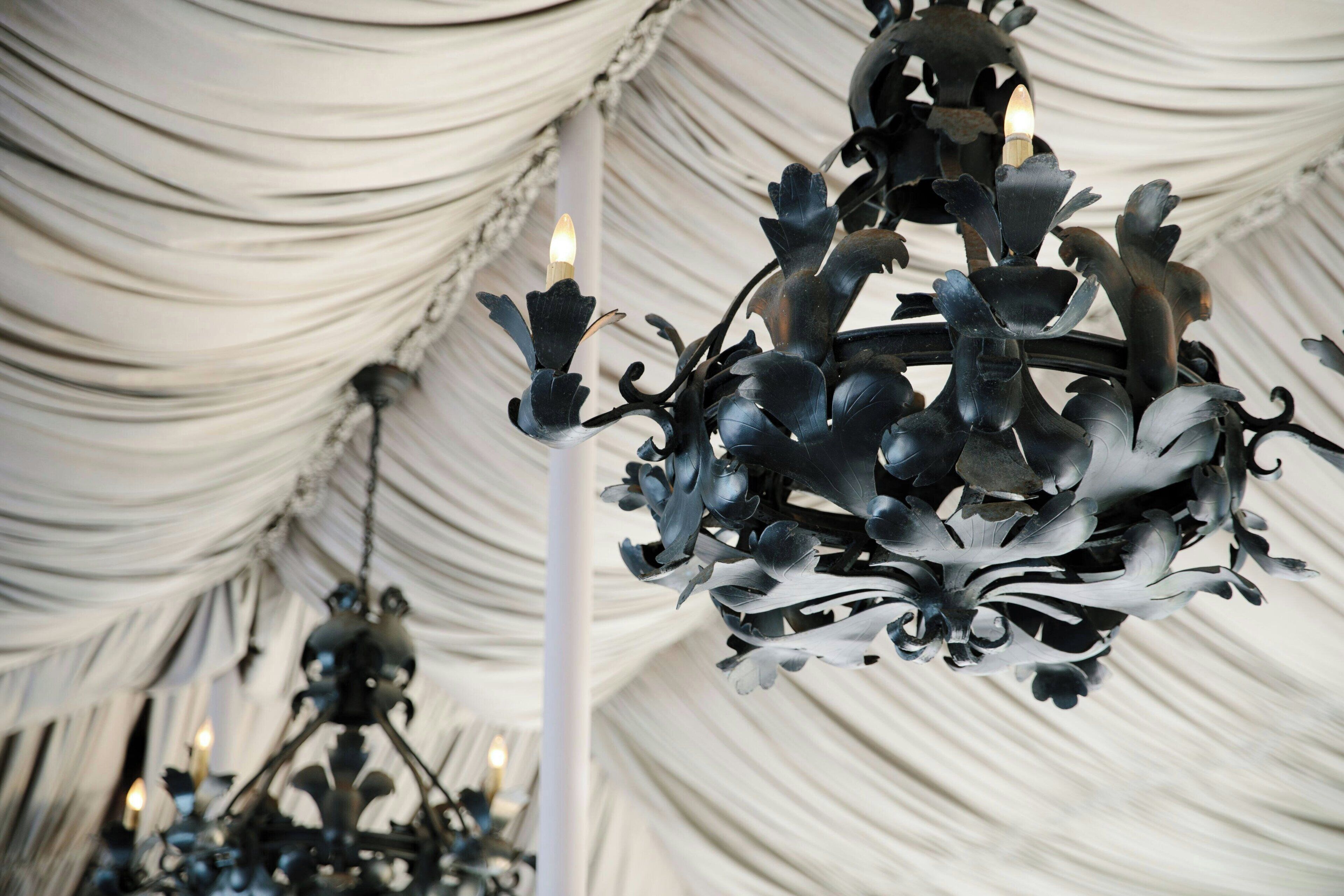 A chandelier with a floral design in a tented structure.