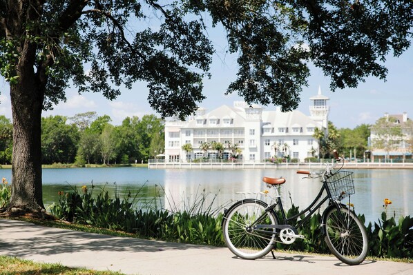 Una bicicleta estacionada junto a un lago, con un edificio al fondo.