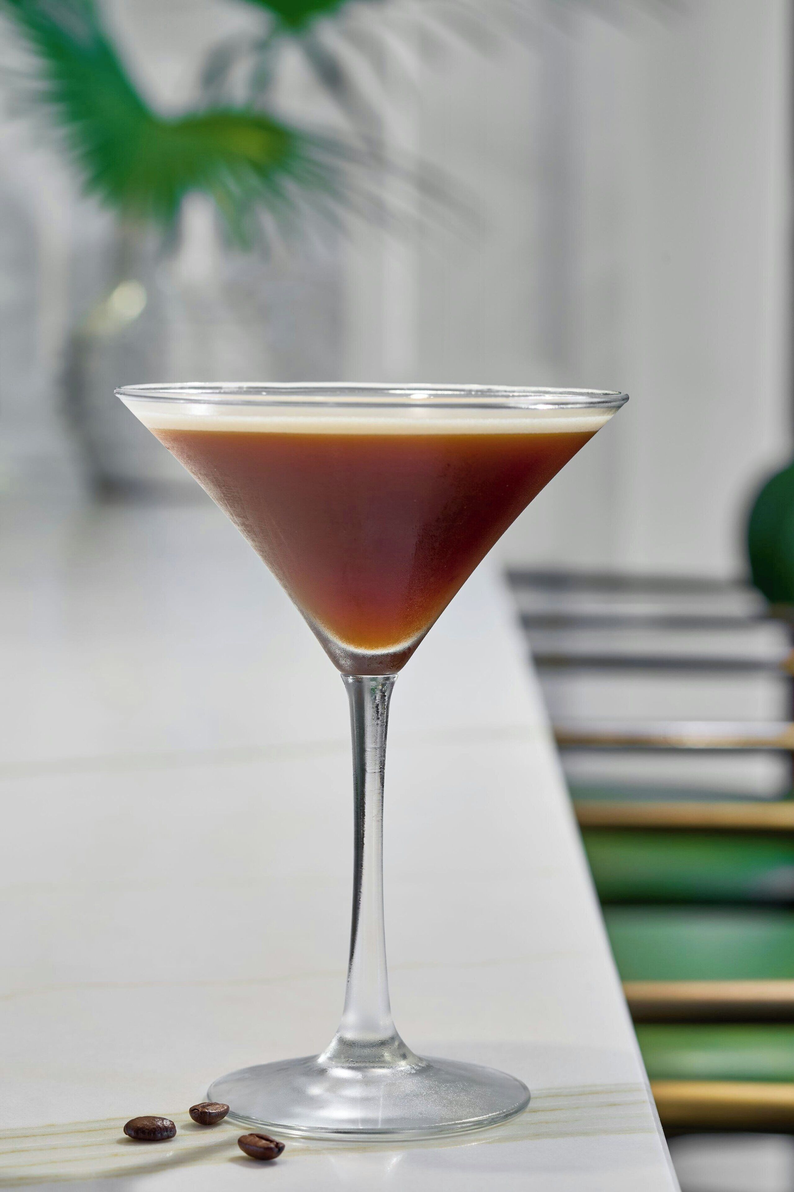 A martini glass with a layered drink on a marble surface.