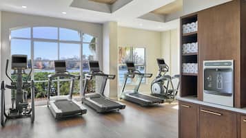 A modern gym with treadmills, a rowing machine, and a water dispenser.