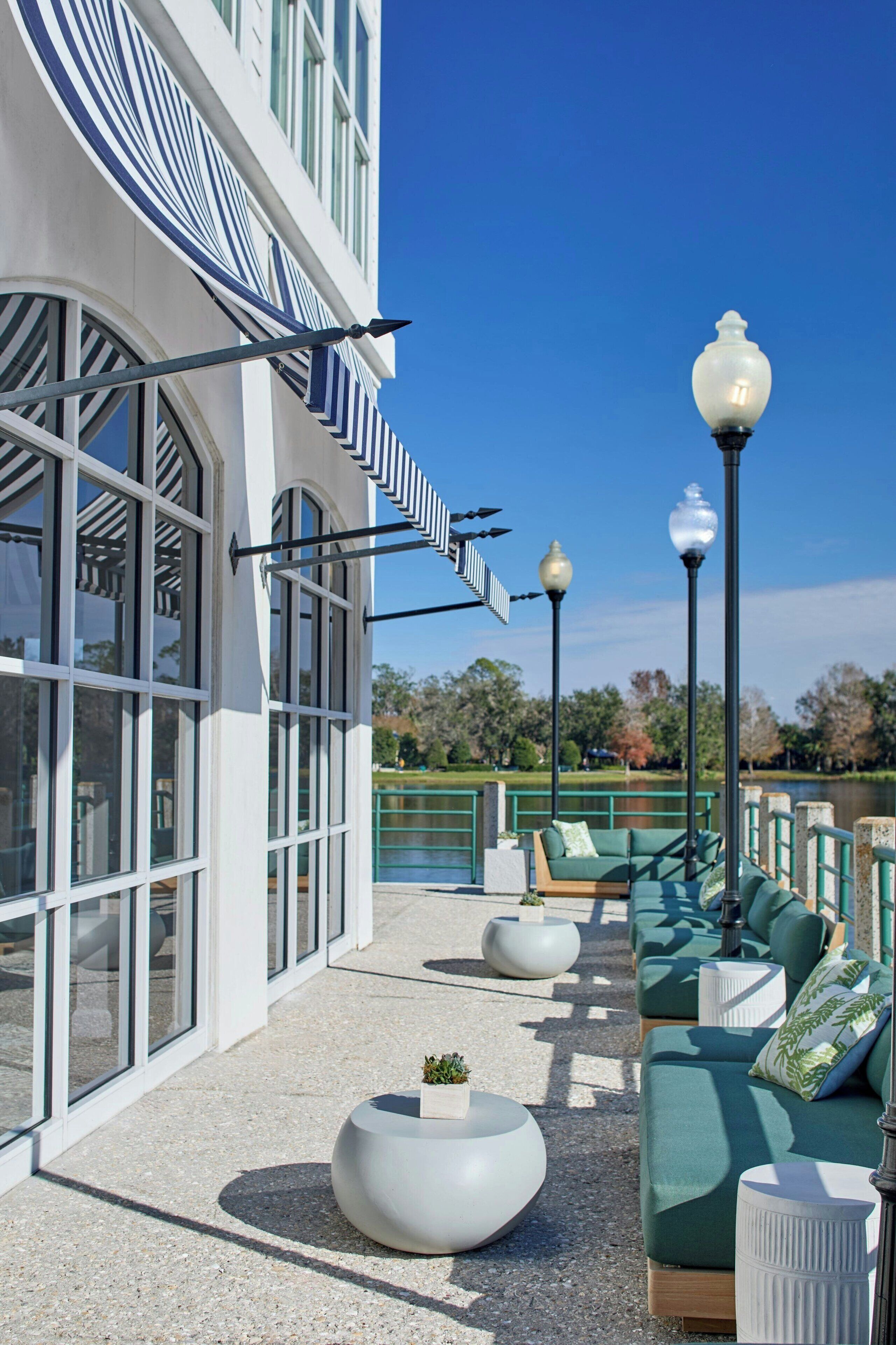 A modern outdoor seating area with a pool, a building with large windows, and street lamps.