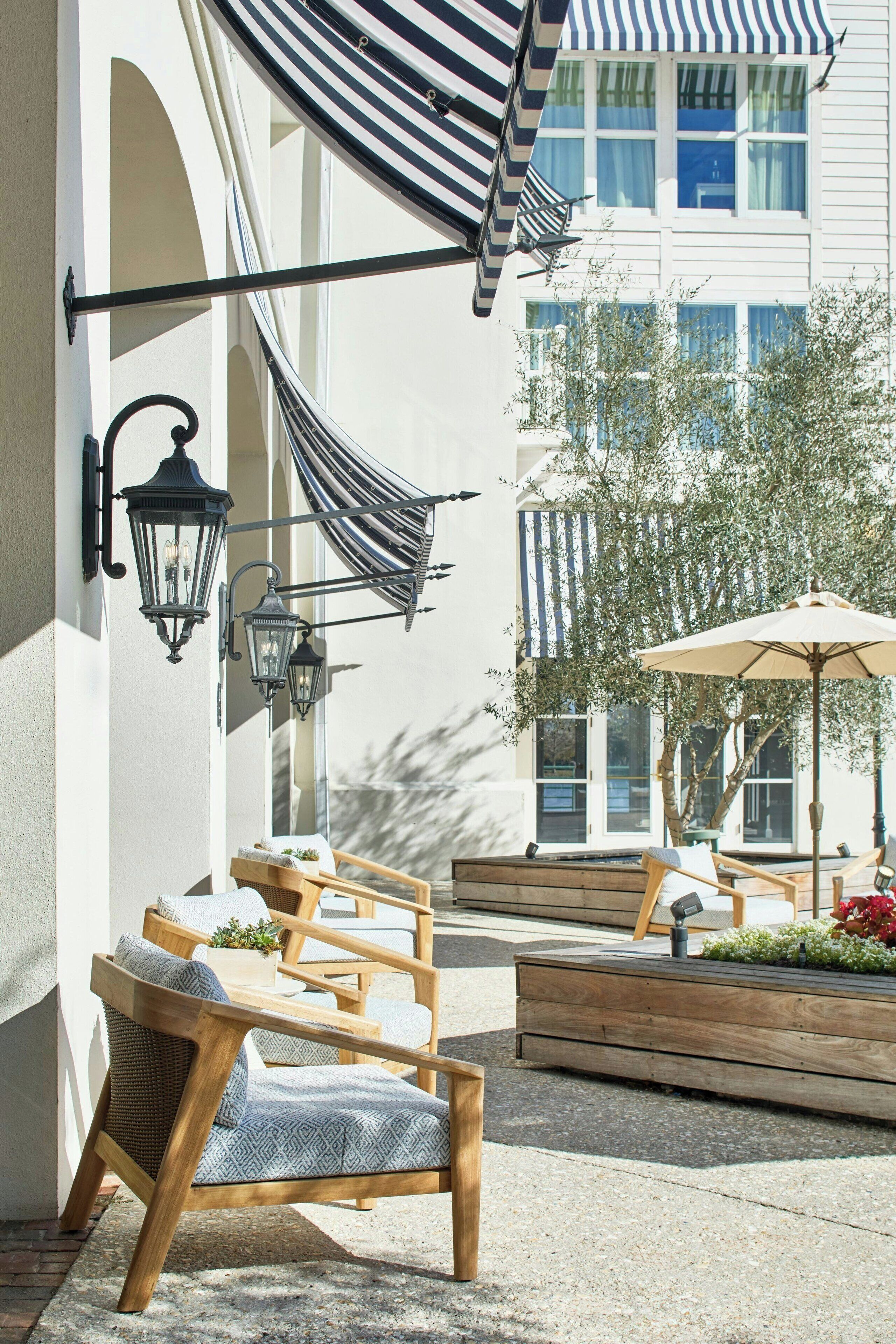 An outdoor seating area with wooden furniture and a striped awning.
