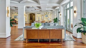A spacious living area with a wooden console table, a grey sofa, and a large plant. - The Inn at Celebration, Autograph Collection  (Celebration)