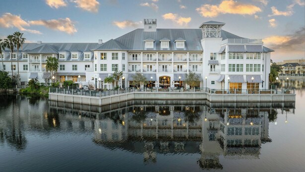 A waterfront hotel with multiple buildings, balconies, and a reflection in the water. - The Inn at Celebration, Autograph Collection  (Celebration)