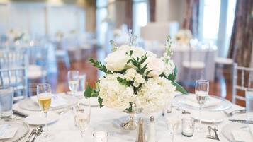 A table set for a formal event with white floral centerpieces, clear glassware, and silver cutlery.