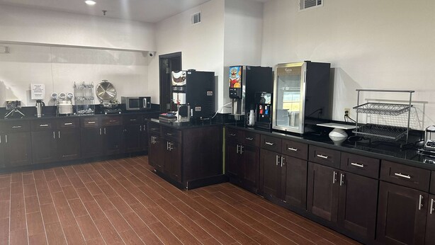 Una cucina moderna con mobili scuri, un frigorifero in acciaio inossidabile, una macchina da caffè e un forno a microonde.
