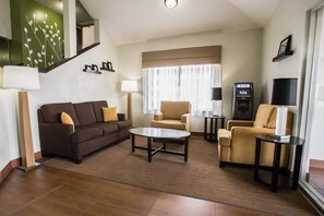 A modern living room with a sofa, armchairs, a coffee table, and a staircase with a green wall design. - Sleep Inn Rockford I-90 (Rockford)