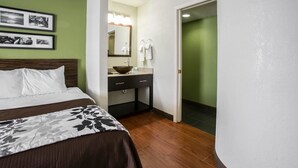 Une chambre d’hôtel avec un lit, une coiffeuse avec un miroir et un mur vert.