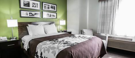 A hotel room with a large bed, two bedside tables with lamps, a chair, and a window with curtains.