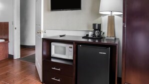 Une petite cuisine équipée d’un four à micro-ondes, d’un réfrigérateur et d’une machine à café, le tout installé sur un plan de travail en bois.